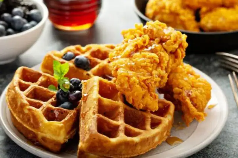 Chicken and waffles served with syrup, featured in a guide to Pigeon Forge breakfast spots.

