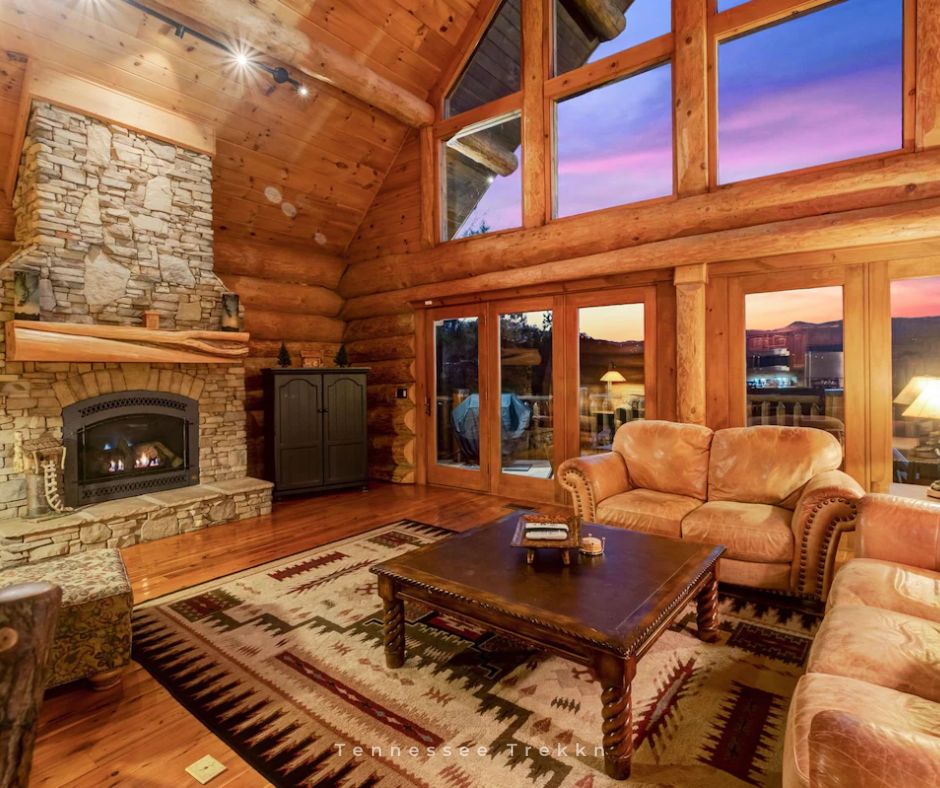 Dancing Bear Retreat Luxury Lodge: Unwind by the stone fireplace while enjoying beautiful views through the wall of windows.