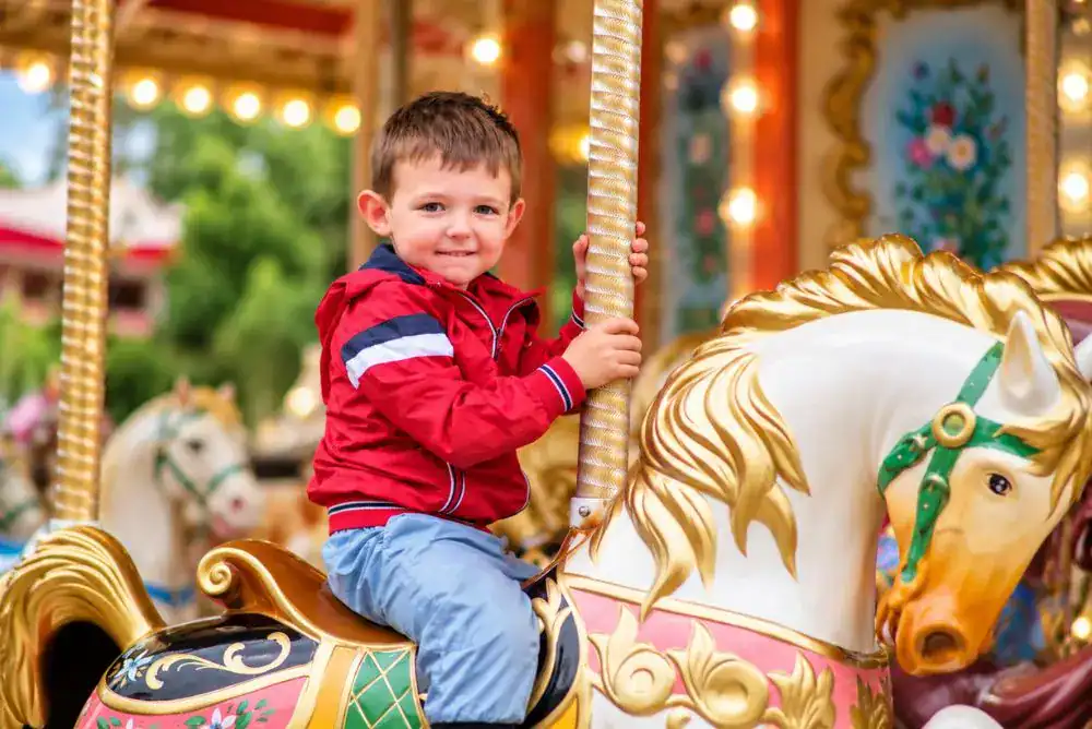 Young boy smiling while riding a colorful carousel horse at Dollywood.