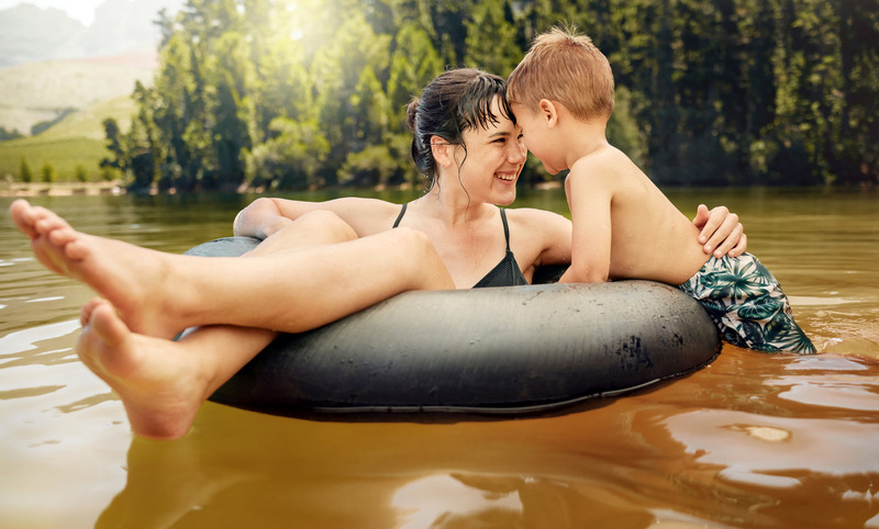 mother and son floating on a round tube in the river. Mom and son enjoying camping vacation tubing in the river.