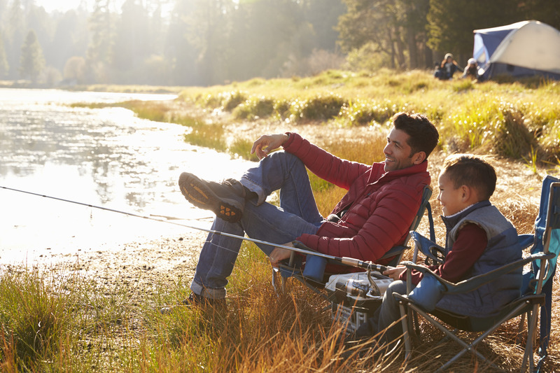 Father and son sitting on the creekbank enjoying fishing together.  Camping in the Smoky Mountains