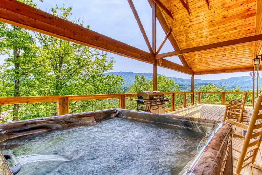 Covered deck with hot tub and Smoky Mountain views at a large group cabin in Gatlinburg, TN