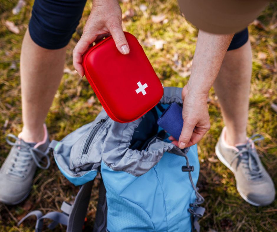 hiker placing first aid kit into their backpack. Hiking essentials.