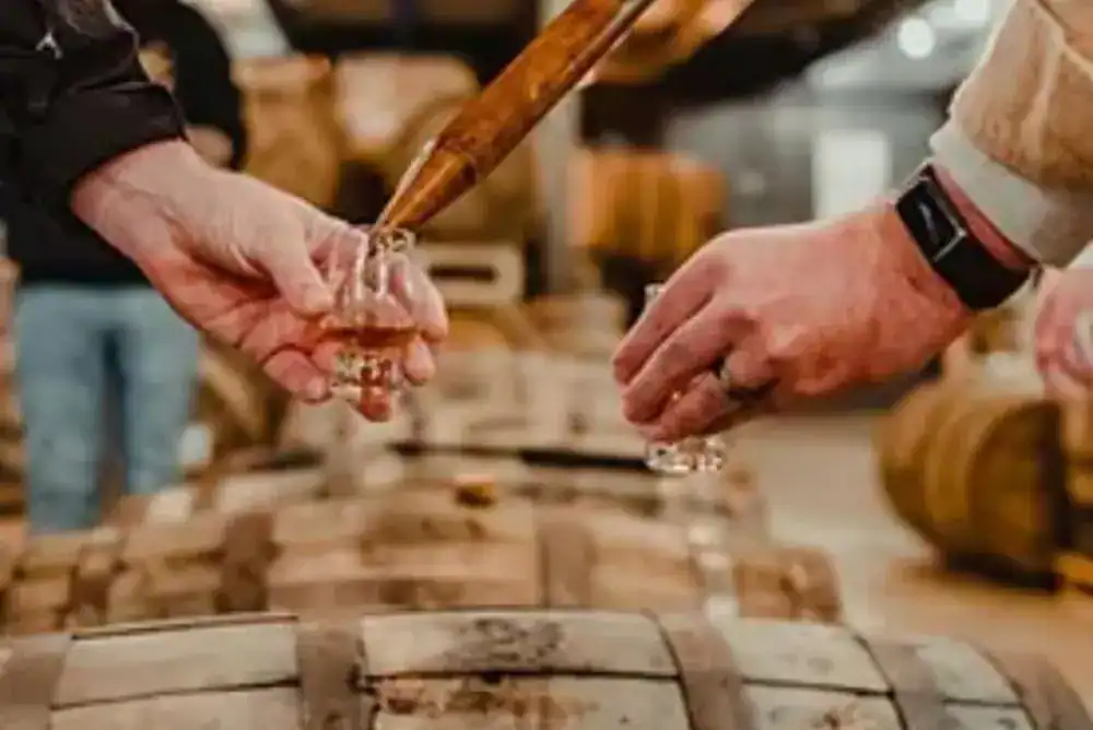 Person pulling a Tennessee whiskey sample straight from a barrel for a Nashville whiskey tours and tastings guide