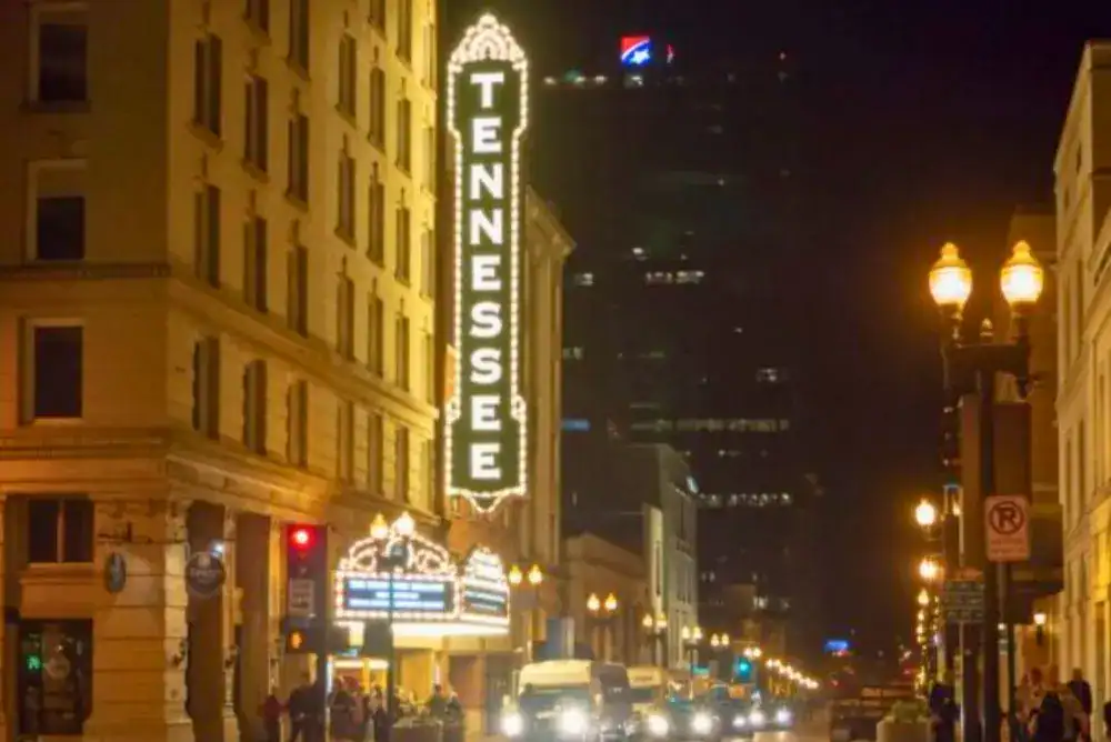 The illuminated Tennessee Theatre marquee lighting up Gay Street at night, with historic streetlamps and downtown Knoxville storefronts lining the sidewalk a iconic spot for history lovers