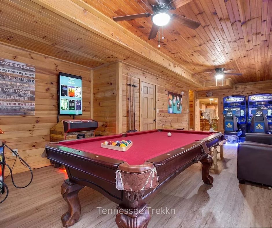 Game room at Bear Country Lodge featuring pool table, arcade games, and seating.