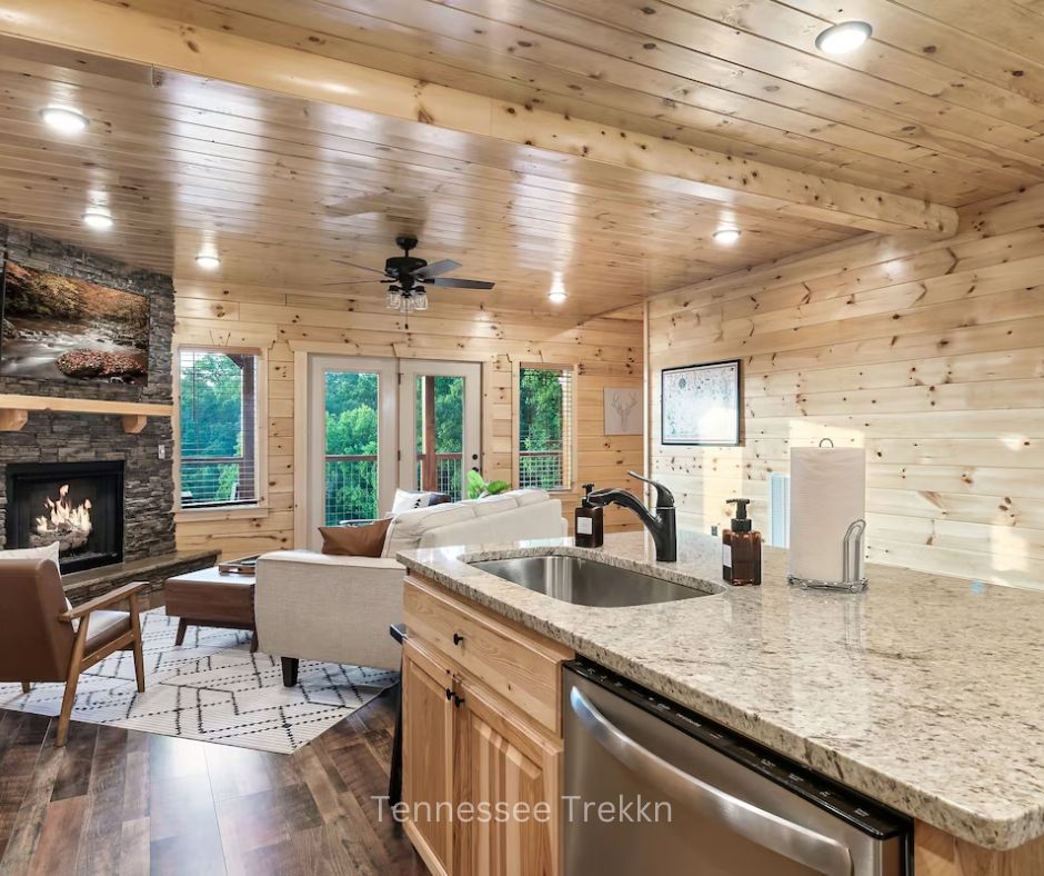 Spacious kitchen and living room with cozy fireplace, modern furnishings, and open layout at Cliffhanger Cabin. Chalet Village Gatlinburg Cabin.