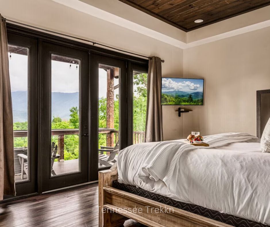 Wake up to stunning views in this cozy bedroom. Book HERE to experience comfort and the beauty of the Smokies. Chalet Village Gatlinburg Cabin Bedroom.