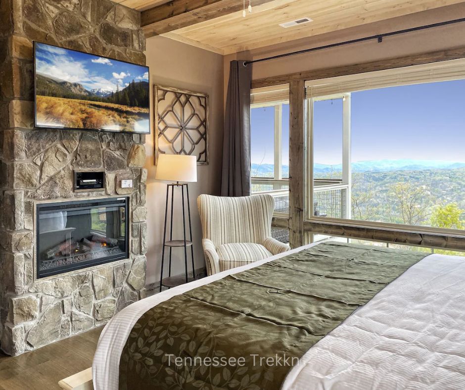 Bedroom at Heaven’s Perch with fireplace, large window, and panoramic views of the Smoky Mountains. Chalet Village Gatlinburg Cabin.