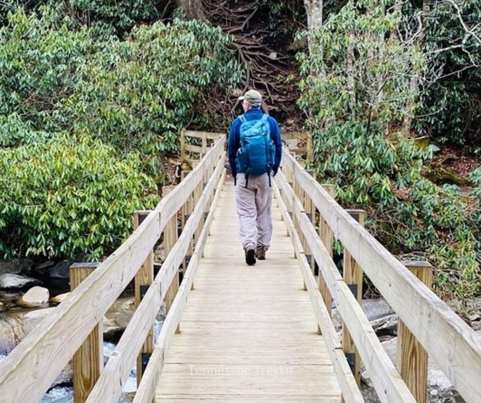 Hiker walking over a wooden bridge on a guided trail in the Smoky Mountains.