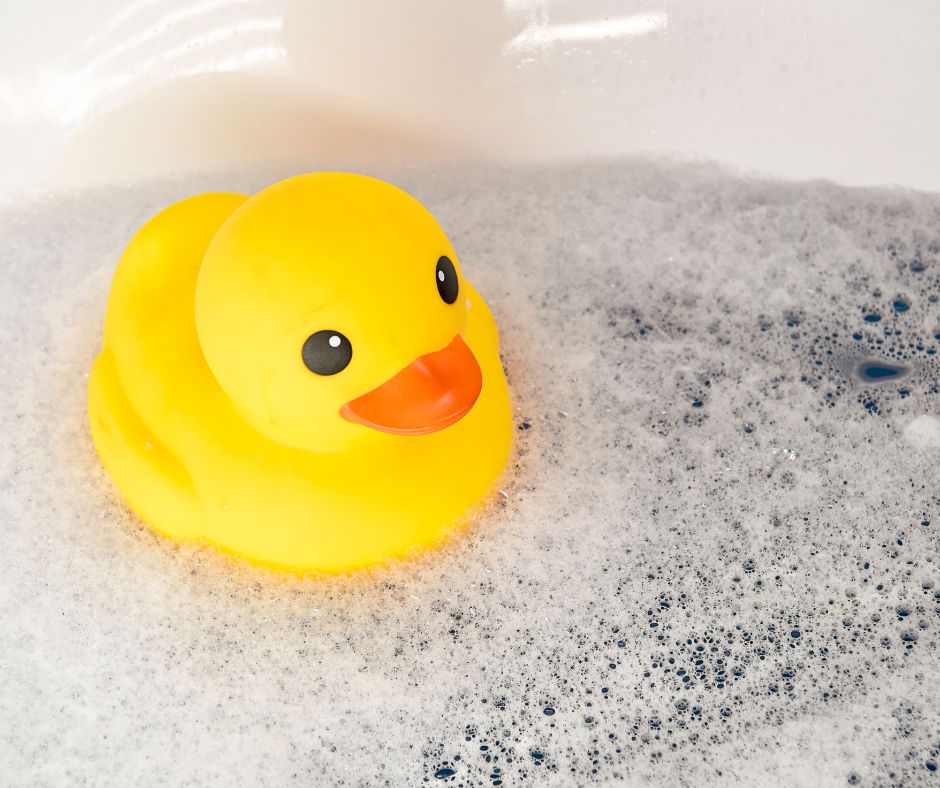  A fun yellow rubber duck floating in a bubble bath, paired with The Bath Lab’s products.