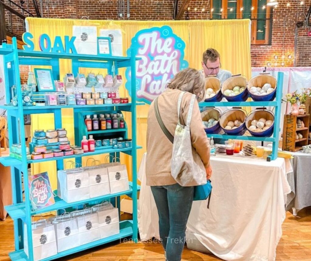 A customer shopping at The Bath Lab’s pop-up event, browsing handmade bath and body products.