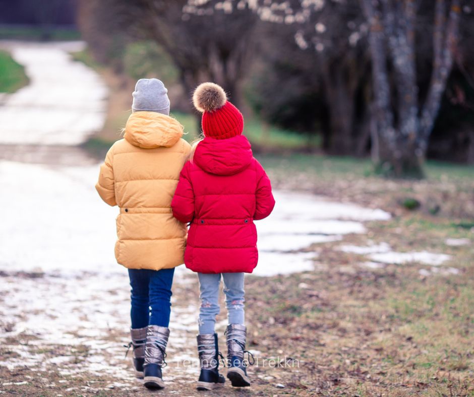 Two people bundled up in warm clothing while hiking a scenic trail in the Smoky Mountains during Christmas-time.