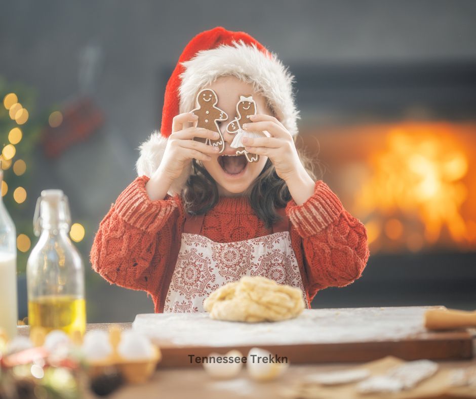 Little girl wearing an apron and holding Christmas sugar cookies over her eyes, enjoying the holiday baking tradition.