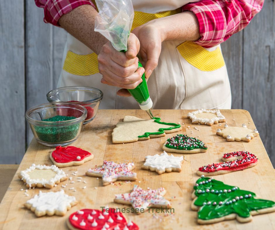 Hands decorating Christmas sugar cookies with colorful icing and sprinkles, made using an easy sugar cookie recipe.