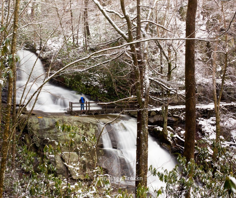 A scenic wintertime view of Laurel Falls Trail in the Smoky Mountains with frosty trees and a cascading waterfall.