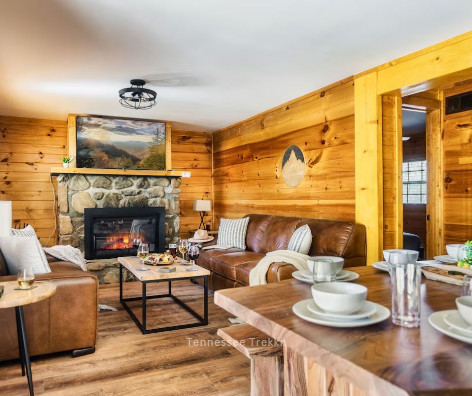 A cozy living room at Pine Splendor featuring a fireplace, plush furniture, and a dining area for holiday gatherings. Christmas Cabins in the Smokies!