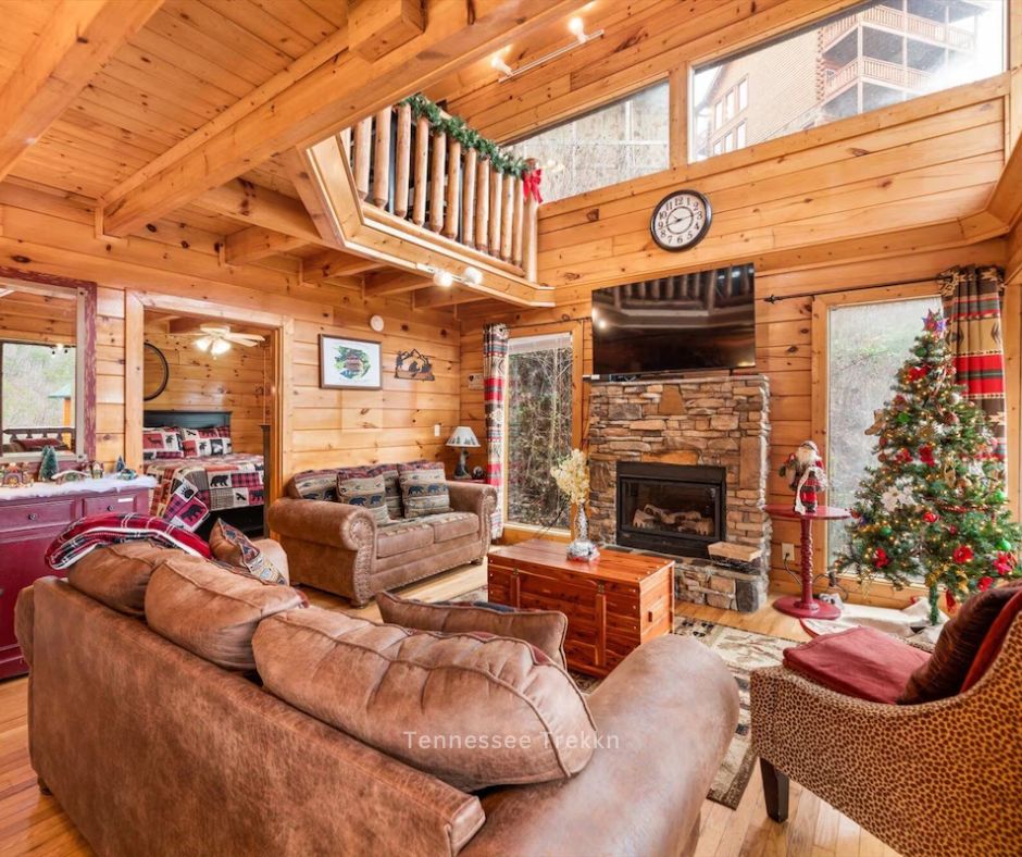  A warm living room with plush couches, a glowing fireplace, and a beautifully decorated Christmas tree.