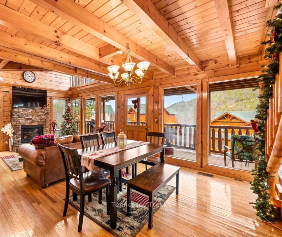 A spacious dining area featuring a rustic table, garland draped along the staircase, and a festive holiday atmosphere.