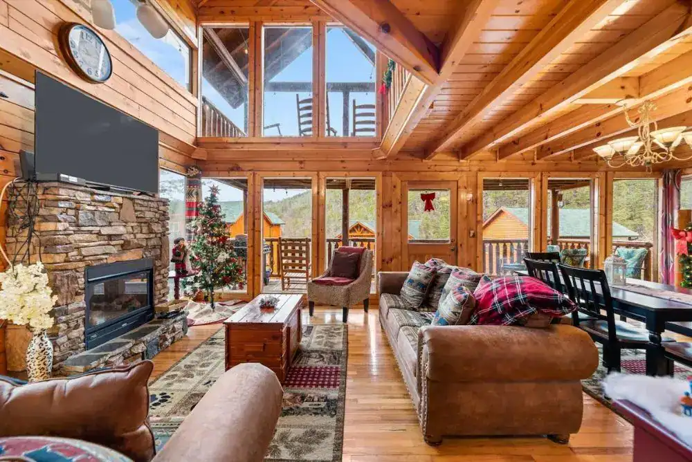 Living area in a Smoky Mountain cabin with large windows and a fireplace. 