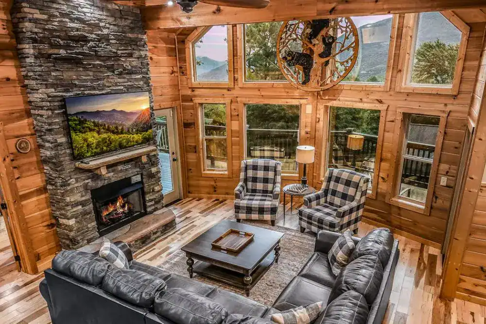 Beautiful and cozy main area in a cabin in the Smokies with fireplace and large windows with mountain views. 
