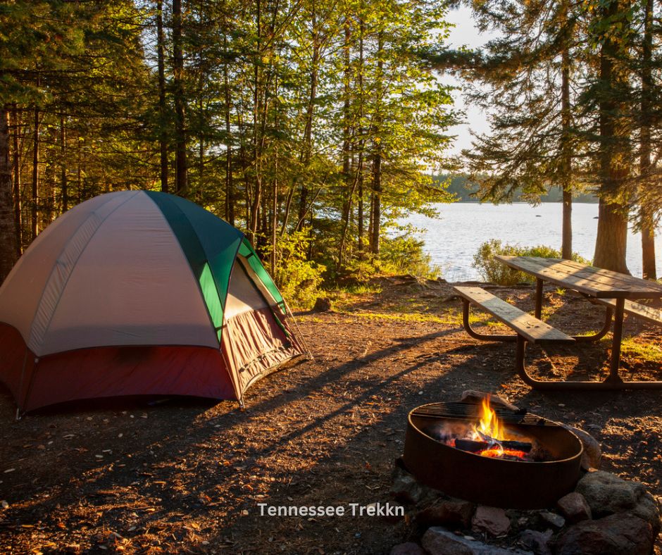 A camping tent set up by a serene lake, showcasing the peaceful outdoor experience at Tennessee state parks.