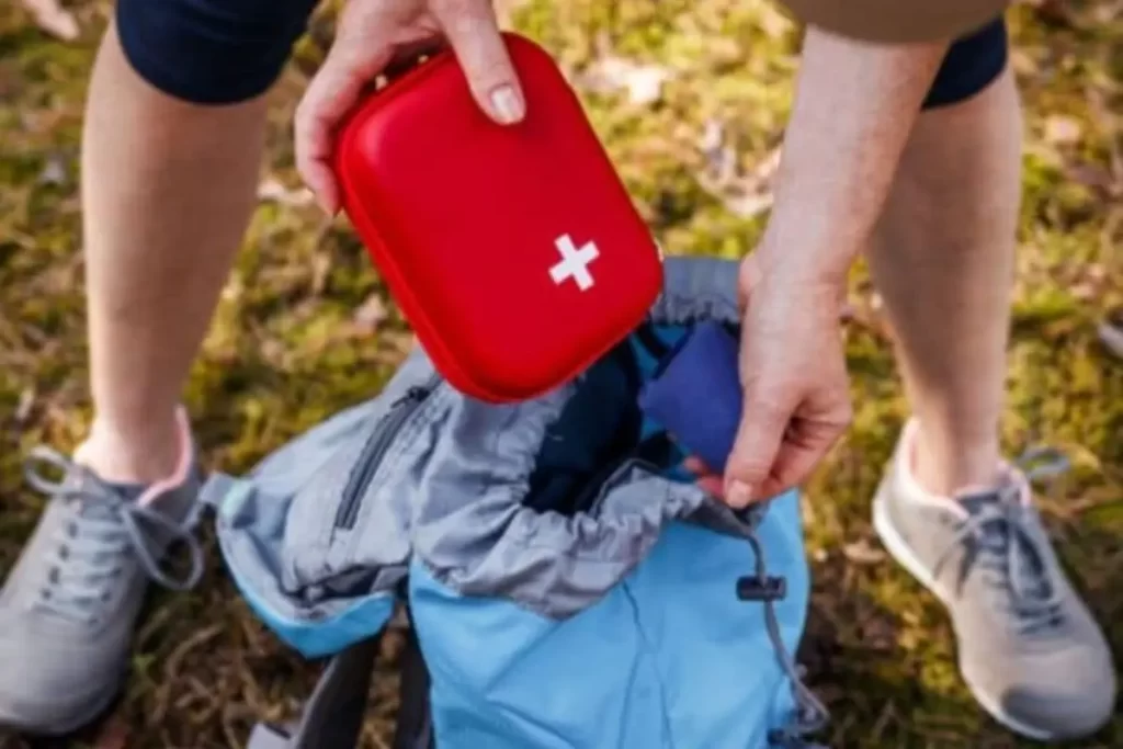 Placing a first aid kit into a backpack, preparing with backpack essentials for hiking in the Smokies.