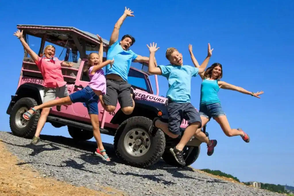 Family jumping in front of a Pink Jeep during a Tour in the Smoky Mountains.

