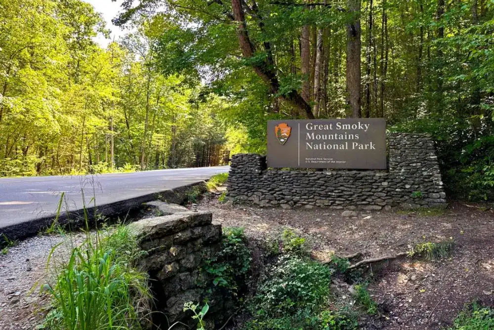 Entrance sign to Great Smoky Mountains National Park with forested background.

