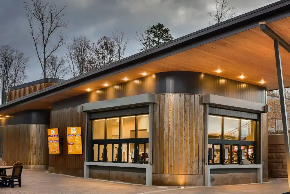 Smoky Mountain Smash restaurant at dusk, its wood-and-glass building glowing warm against a cloudy mountain sky