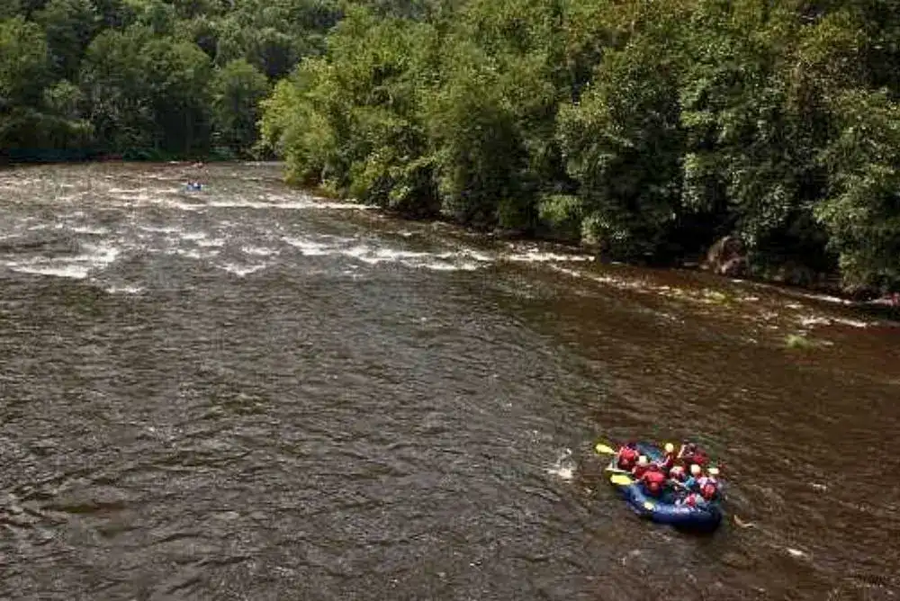 Raft floating through the scenic Lower Pigeon River during a family-friendly white water rafting trip in the Smoky Mountains.