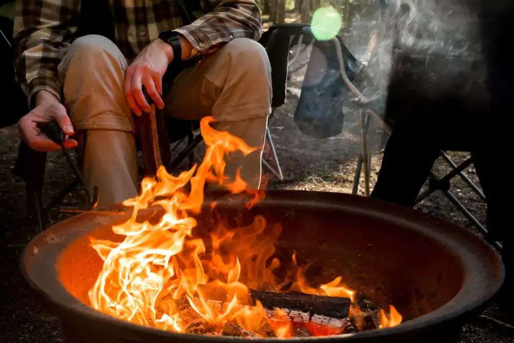 People sitting around a campfire in a fire ring at a Tennessee campsite, practicing safe campfire safety.