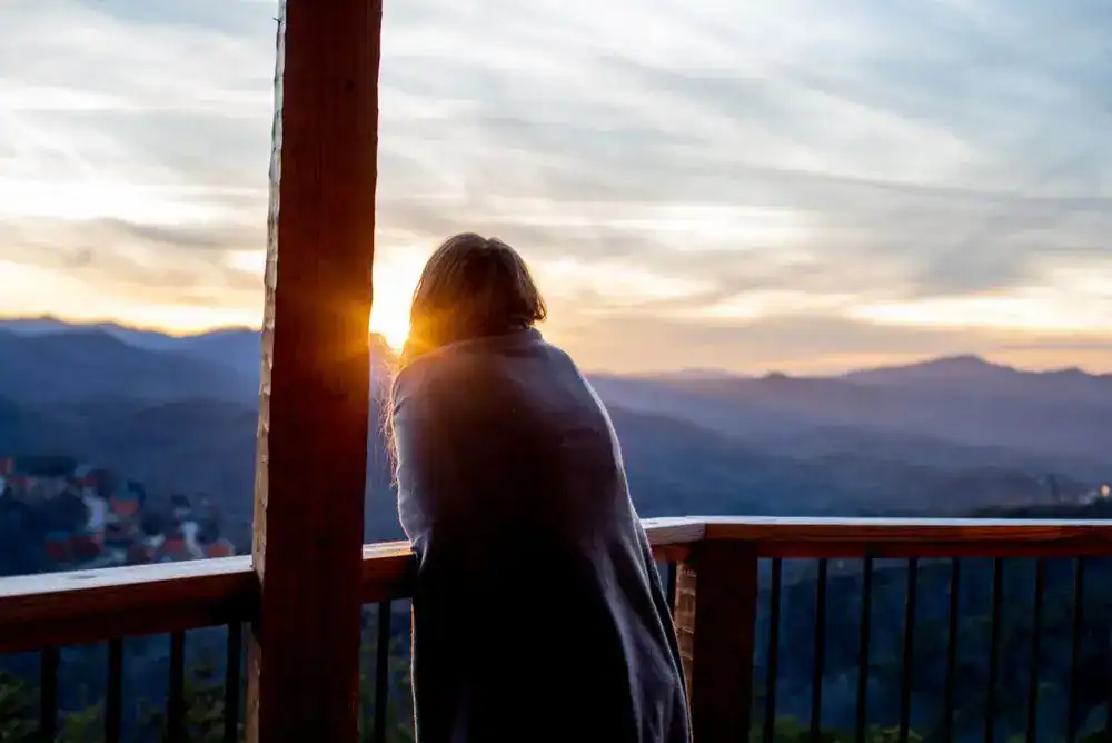 Woman watching sunrise from cozy Townsend cabin in the Smoky Mountains