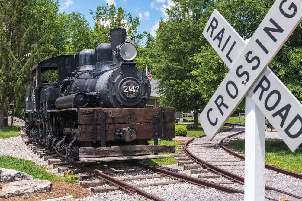 Historic steam locomotive beside a railroad crossing sign at the Little River Railroad Museum in Townsend, Tennessee.