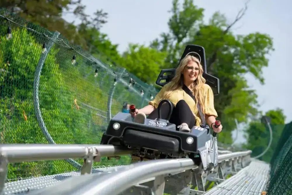Woman riding down the SkyLand Ranch Coaster in Pigeon Forge on a sunny day.