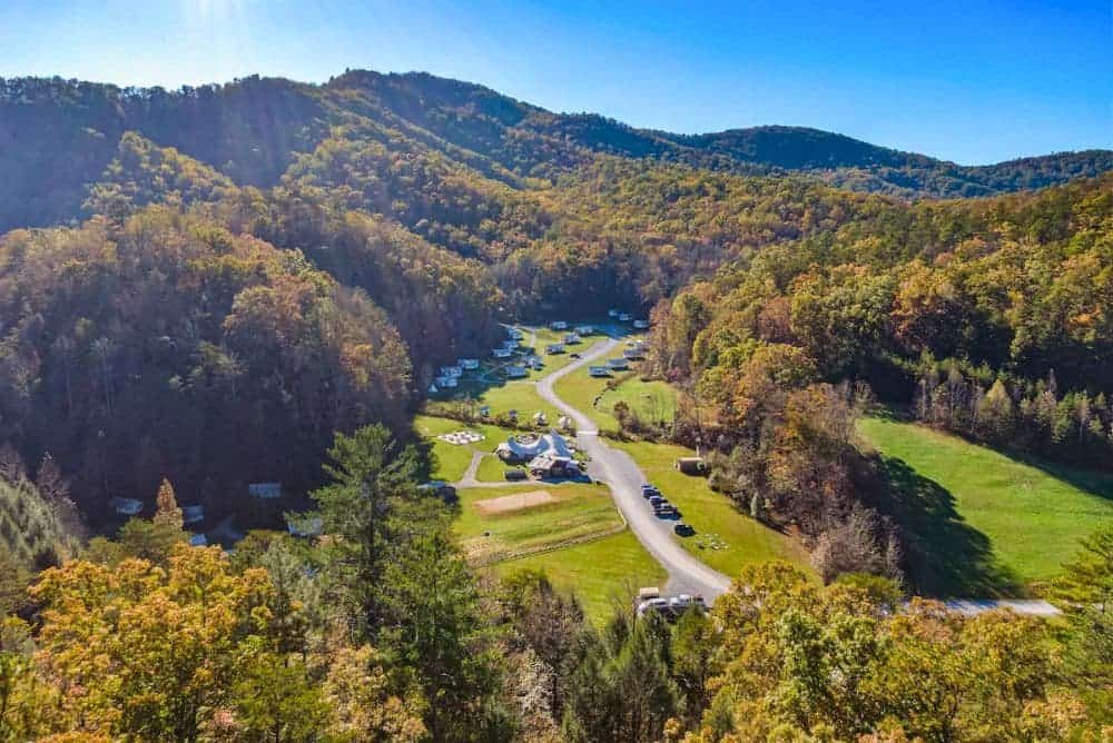 Aerial view of Under Canvas Great Smoky Mountains, with safari tents nestled in a green valley surrounded by forested ridges and fall color near Sevierville.