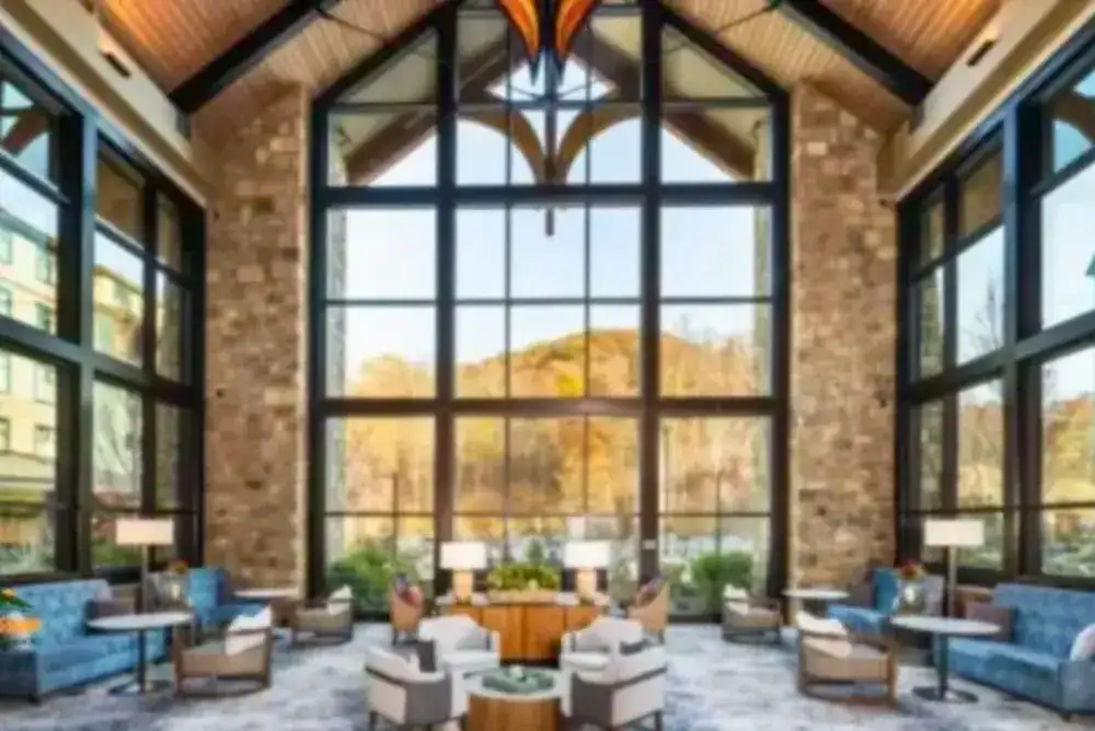 Spacious hotel lobby in with floor-to-ceiling windows, comfortable seating, and mountain views.