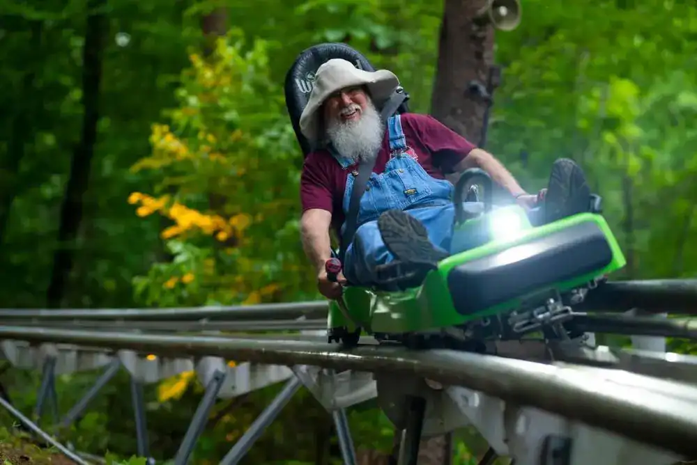 Man riding the Moonshine Mountain Coaster surrounded by fall leaves — thrilling adventure ride.