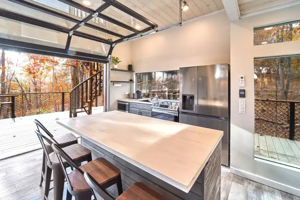 Fully furnished kitchen inside a luxury treehouse getaway with island seating and modern appliances.