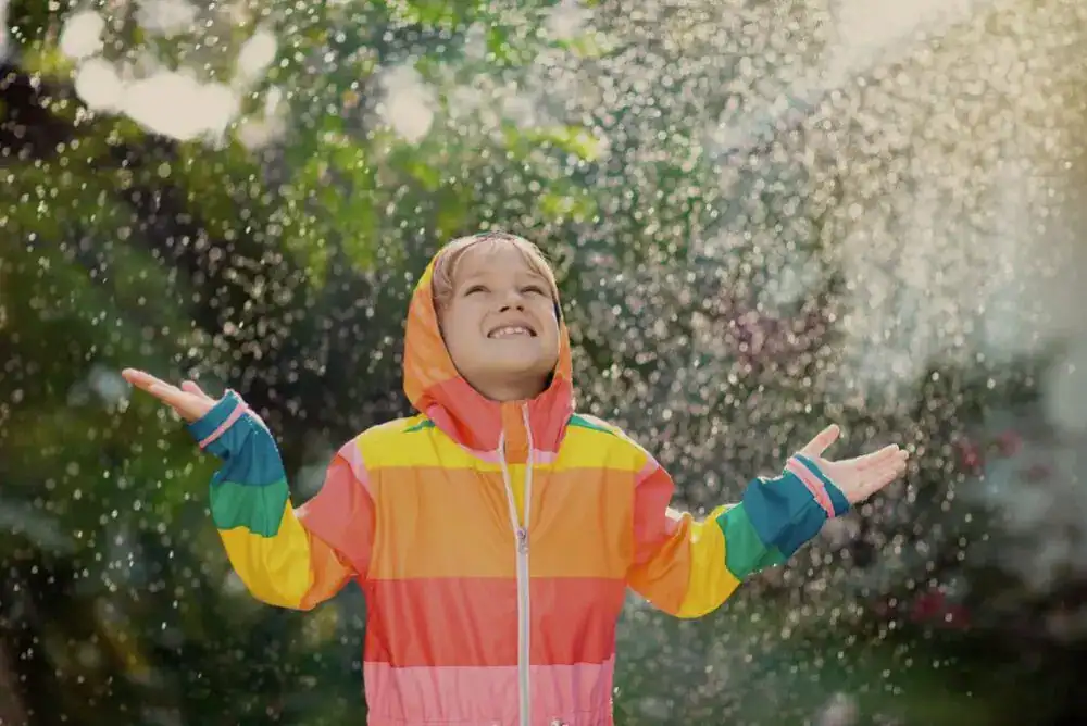Kid wearing a rain jacket and playing outside in the rain.
