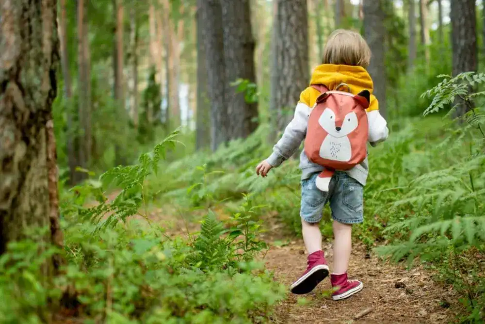 Kid wearing a backpack on a trail, showing one of our favorite hiking and outdoor gifts for kids guide.
