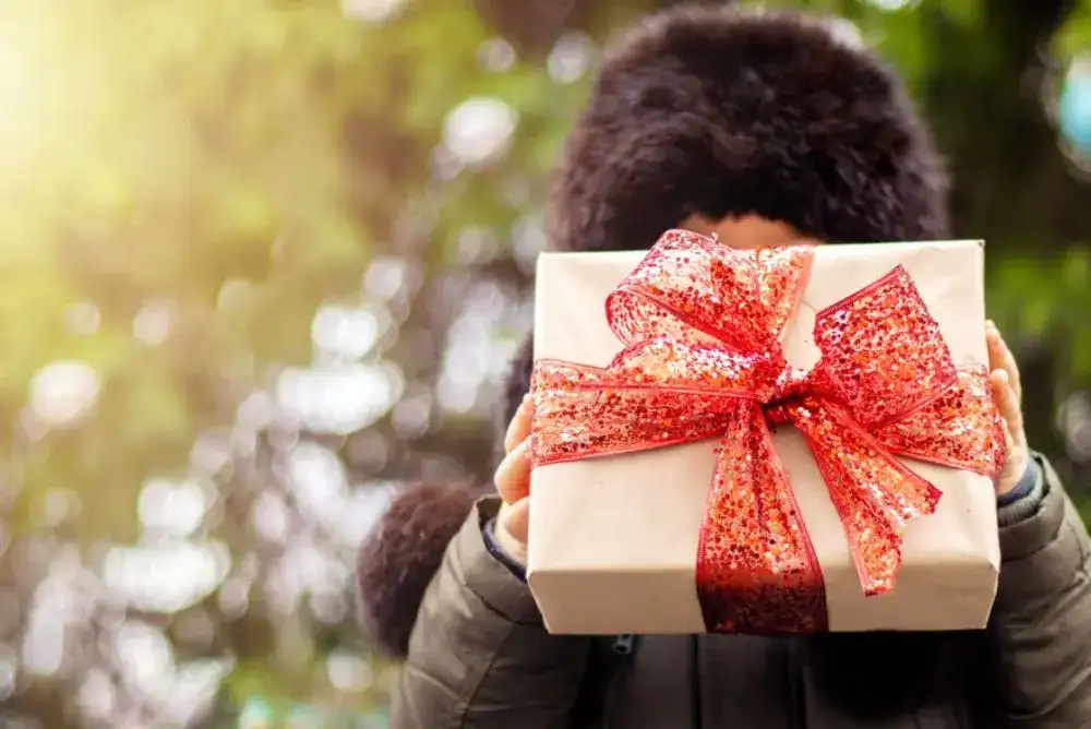 Kid holding a Christmas gift outside to introduce our outdoor gifts for kids guide.
