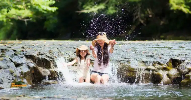 Kid-friendly destinations in Tennessee — mom and daughter splashing in a Smoky Mountain creek