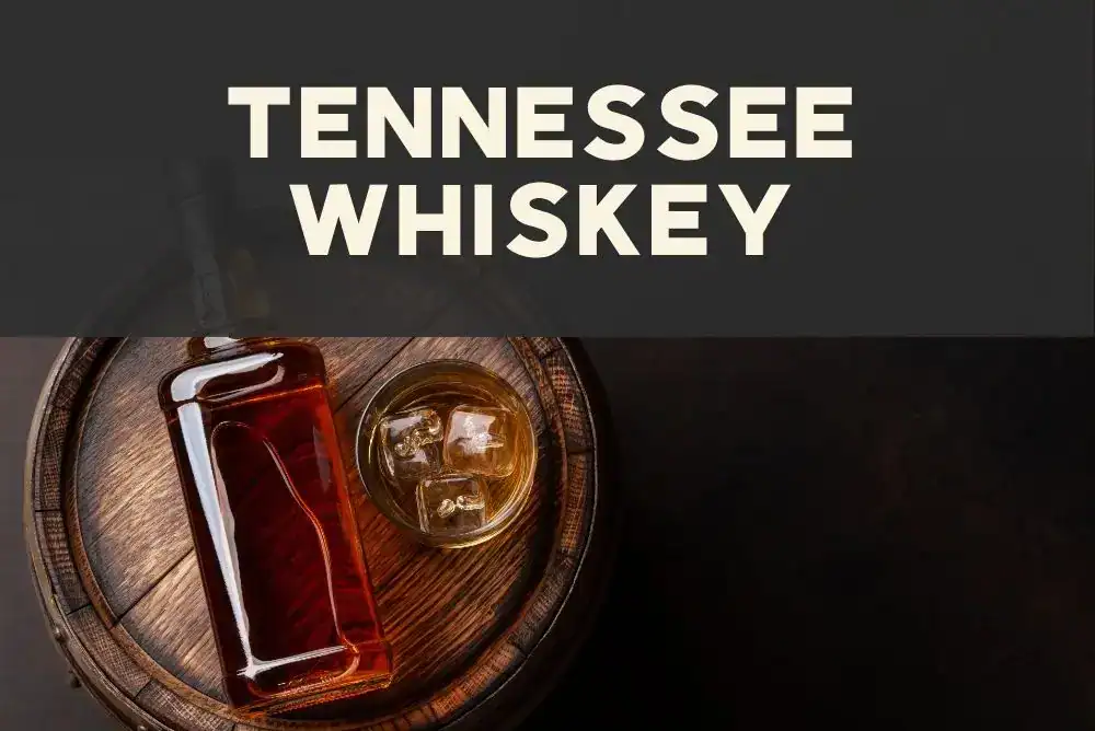 A whiskey barrel and glass of Tennessee whiskey sitting on a rustic wooden surface at a distillery