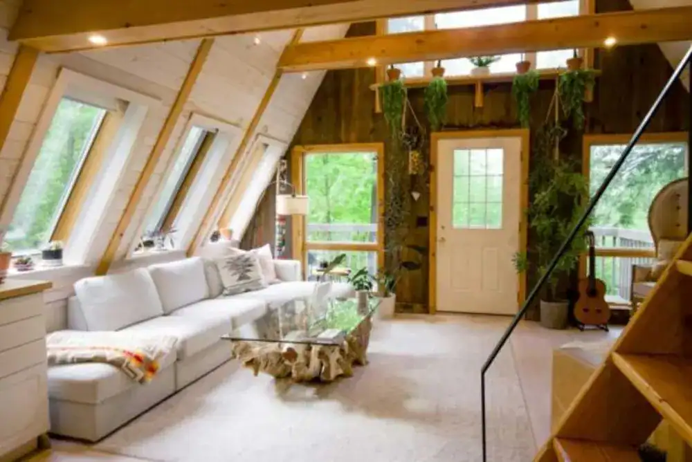 A-frame cabin living room with angled windows and forest views, one of the unique places to stay in Tennessee