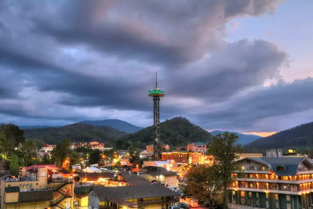 Downtown Gatlinburg lit up at night with Smoky Mountains in view. 
