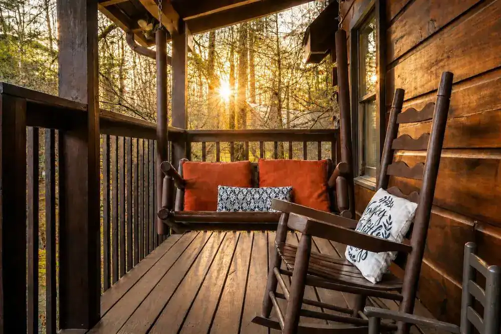Cabin porch with a swing and rocking chairs at sunrise, one of the best places to stay in Pigeon Forge near Dollywood
