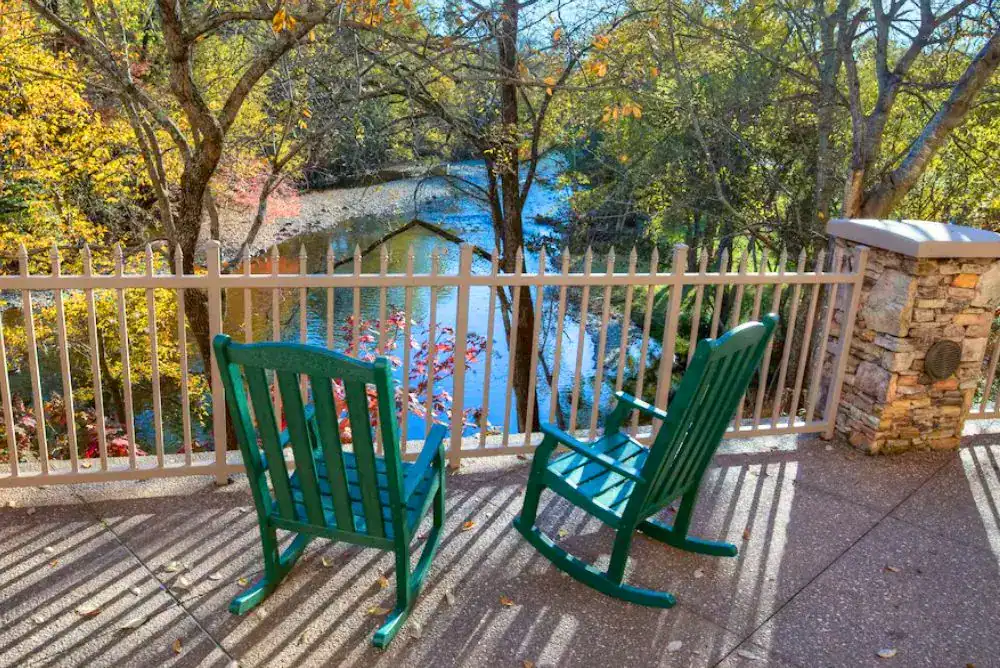 Green rocking chairs on a riverside patio at Music Road Resort Hotel, one of the riverfront hotels in Pigeon Forge