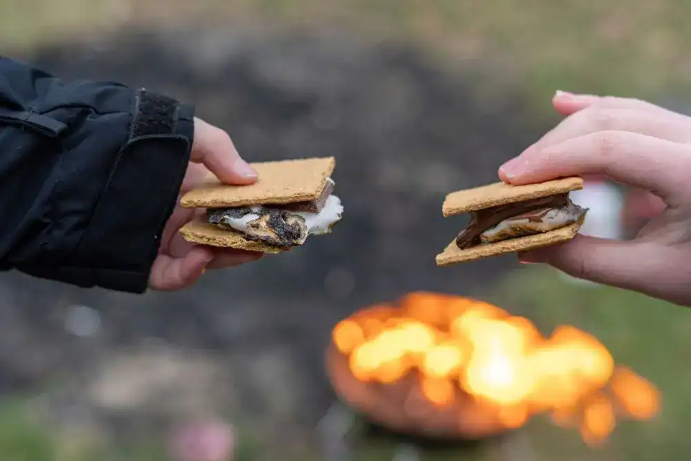 S’mores being enjoyed around a campfire on a cozy fall camping night.