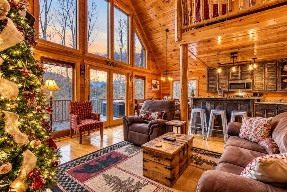 Christmas-decorated Gatlinburg log cabin living room with a large Christmas tree, vaulted wood ceilings, and tall windows.
